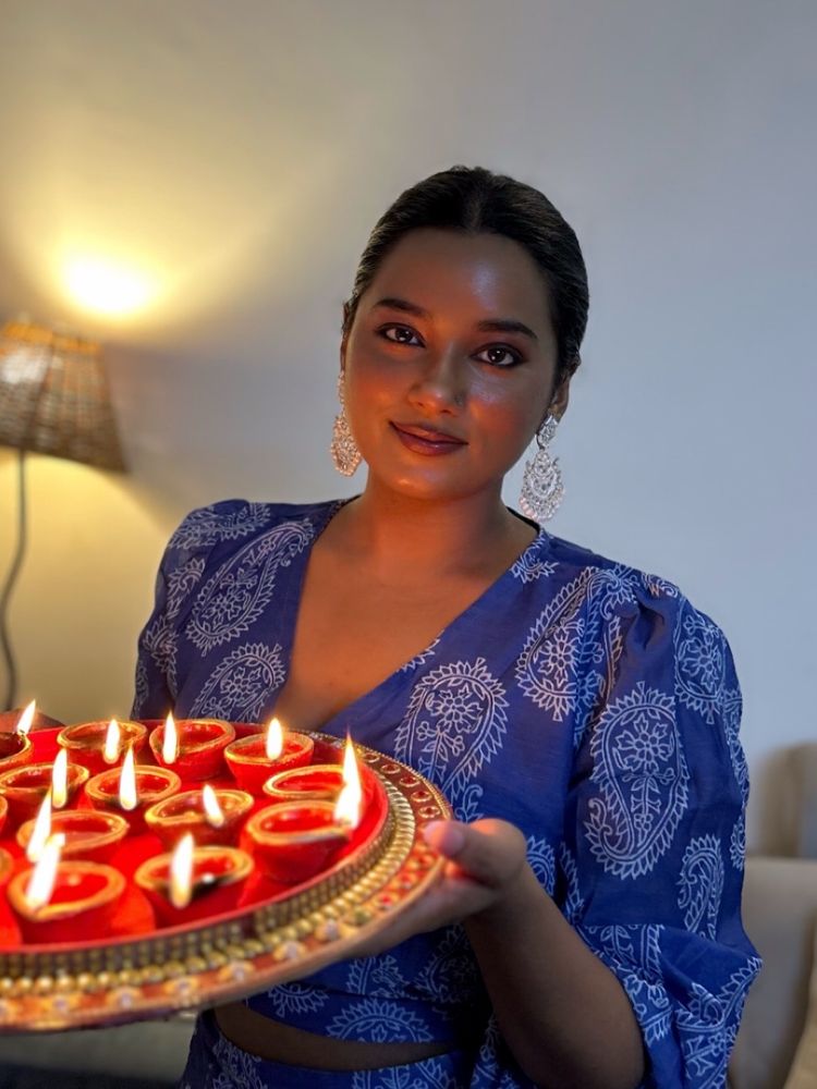 Charuta holding a tray of lit diyas